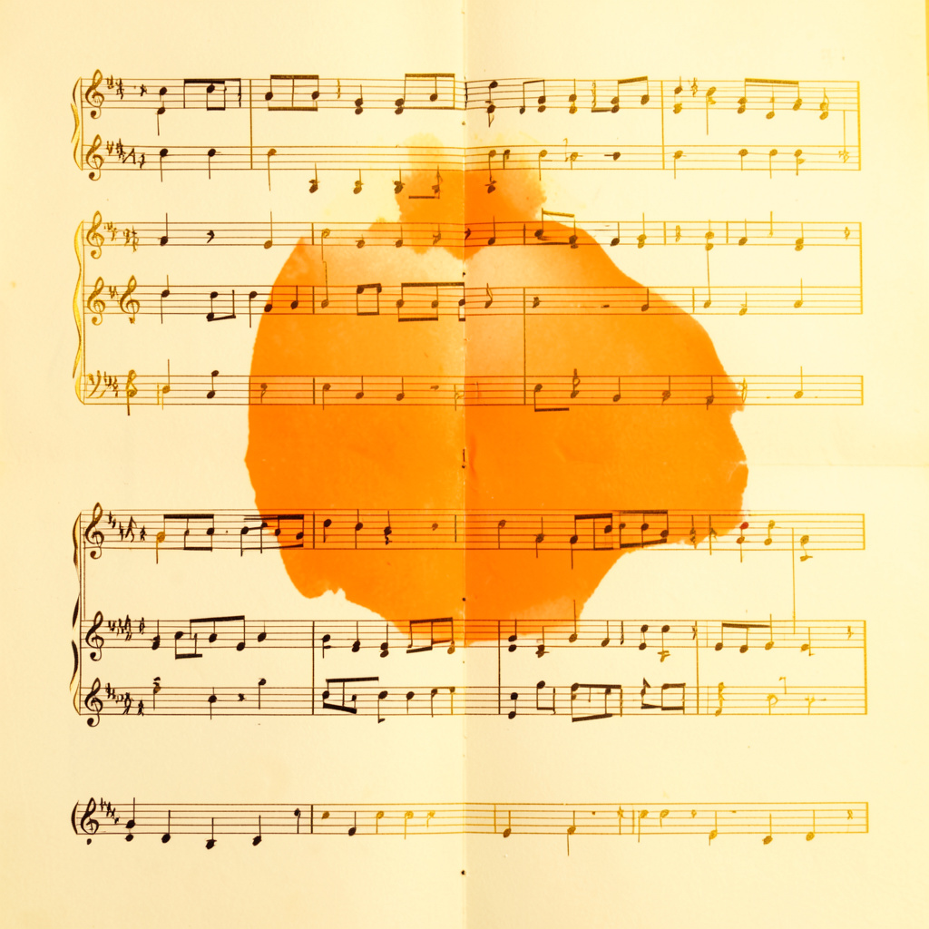 A symmetrical close-up of a printed musical score on cream paper with warm gold accents in the lighting